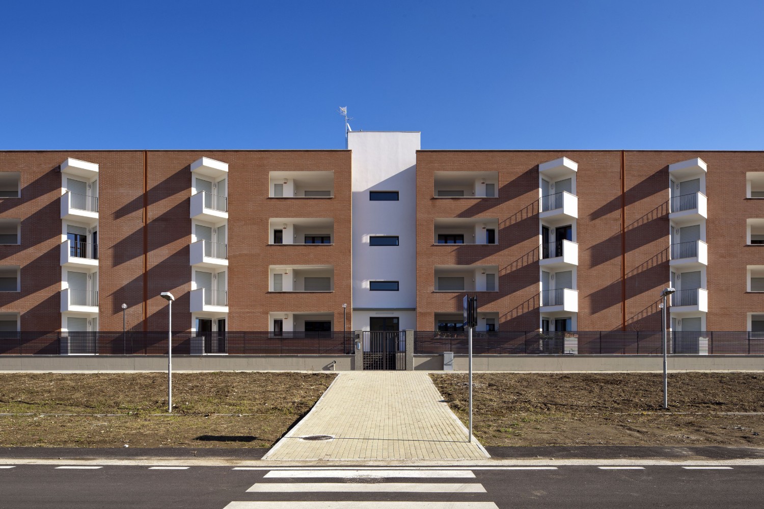Corvino + Multari, studio di architettura a Napoli: 24 alloggi di edilizia residenziale pubblica a Quarto, nei Campi Flegrei, con mattoni a vista e basamento in pietra vulcanica