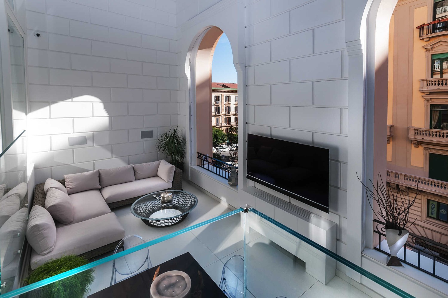 Imperatore Architetti, studio di architettura a Napoli: soggiorno di una residenza privata con finestre ad arco affacciate sui palazzi storici della città