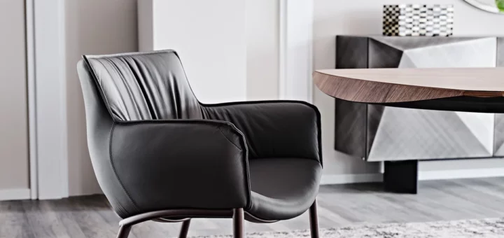 Sedia Rhonda di Cattelan Italia con braccioli imbottiti accanto a un tavolo