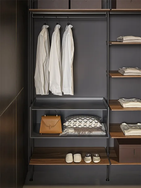 Detail of the open Roll walk-in wardrobe by Bonaldo with hanging shirts, shelves and storage compartments