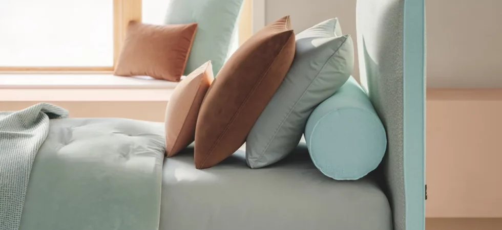 Letto Dread di Twils in una tonalità verde chiaro con cuscini rosa e pareti chiare