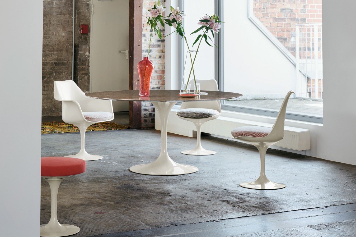 Sedie Tulip di Eero Saarinen per Knoll attorno al tavolo Saarinen con base a stelo in un loft industriale